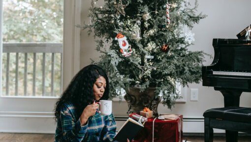 Woman with a book and laptop in front of a Christmas Tree
