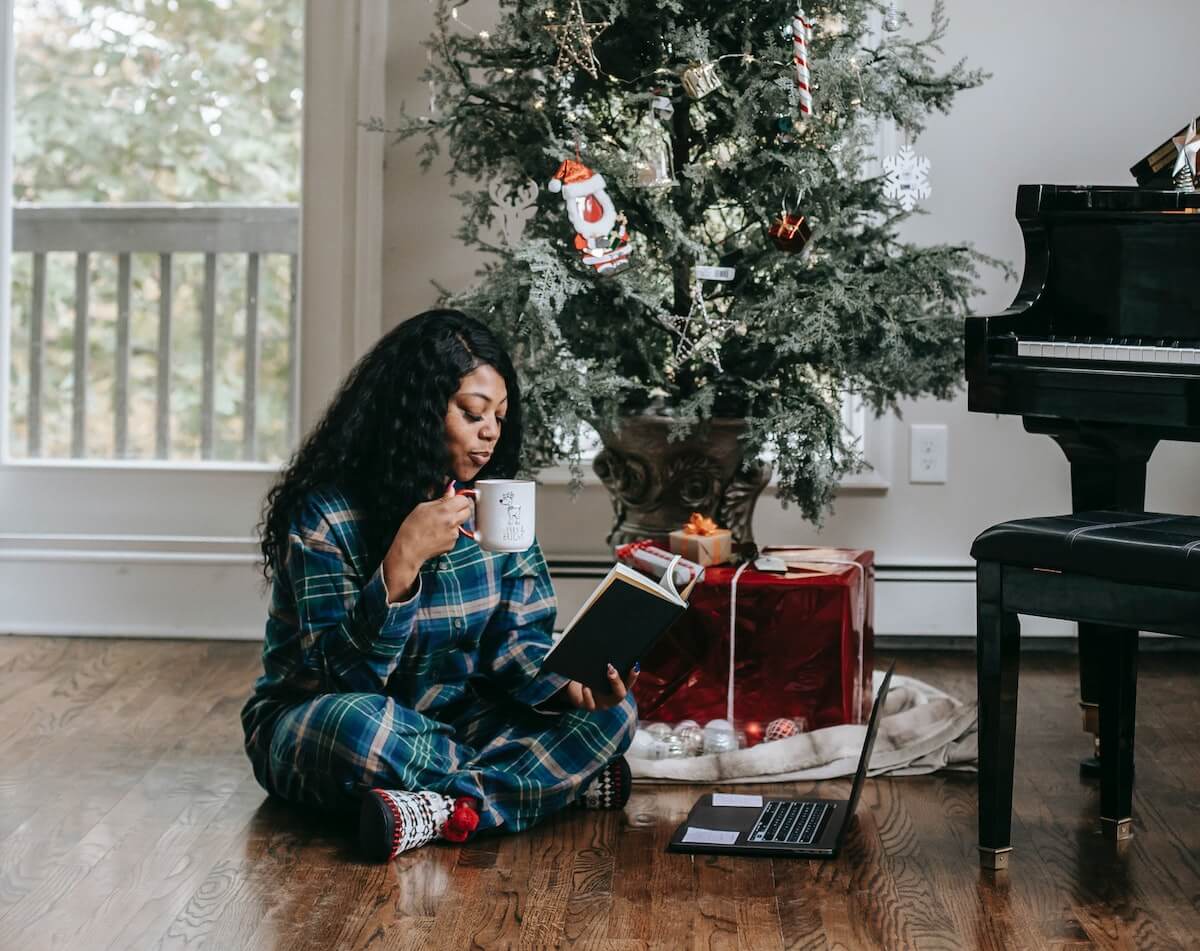 Woman with a book and laptop in front of a Christmas Tree