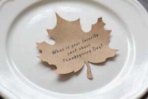 A leaf on a plate with the writing, "What is your favorite part about Thanksgiving Day?"