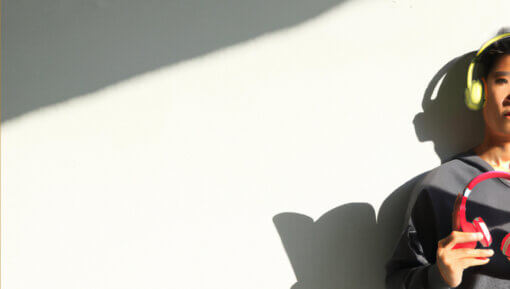 A man wearing headphones with a shadow holding a book