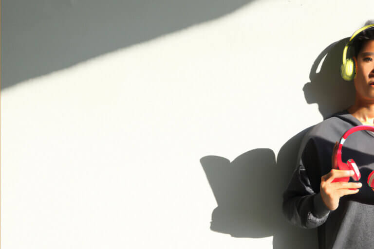 A man wearing headphones with a shadow holding a book