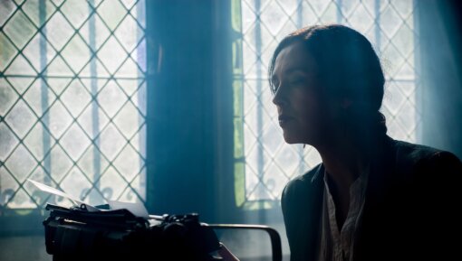 A woman in front of a window with a typewriter
