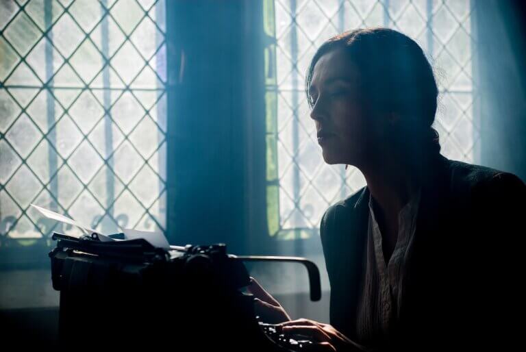 A woman in front of a window with a typewriter